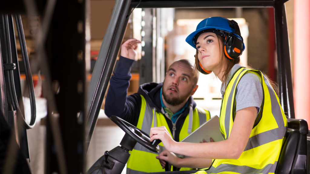 employee training colleague on forklift operations